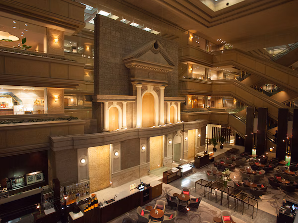 A multi-level hotel lobby with a bar area, seating arrangements, and a grand staircase.
