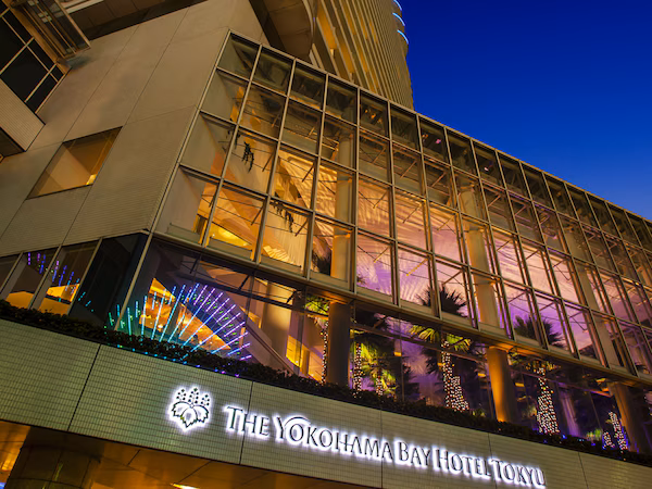 A modern hotel with a prominent glass facade and illuminated signage.