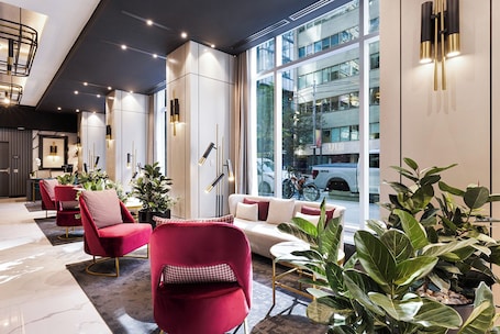 A modern hotel lobby with a seating area, large windows, and a view of the city.