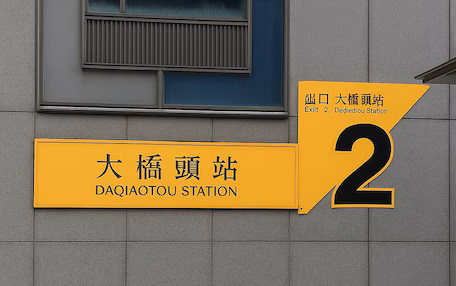 A building facade with a yellow sign indicating "DAQIAOTOU STATION" and the number "2" on it.