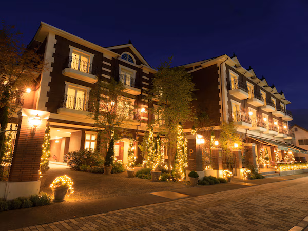 A multi-story hotel with a brick facade, multiple balconies, and outdoor lighting.