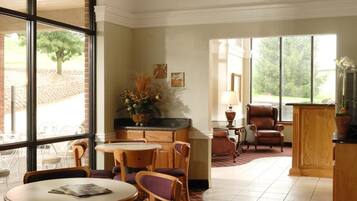 A spacious dining area with high ceilings, large windows, and a chandelier.