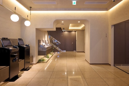 A hotel entrance with a brick facade, outdoor seating area, and potted plants.