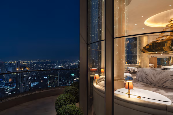 A high-rise hotel room with a city view, a modern interior, and a large, curved sofa.