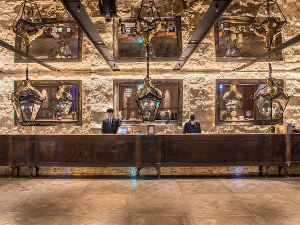 A reception area with a stone wall, multiple hanging lanterns, and a polished wooden reception desk.
