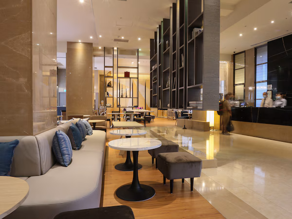 A modern lobby with a seating area, tables, and a reception desk.