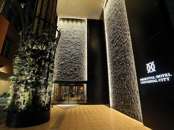 The entrance of Oriental Hotel Universal City with a modern design, featuring a large vertical garden and a textured wall facade.