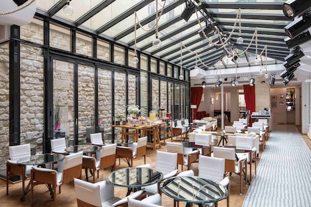 A spacious indoor area with a high ceiling, stone walls, and multiple seating arrangements including round tables and chairs.