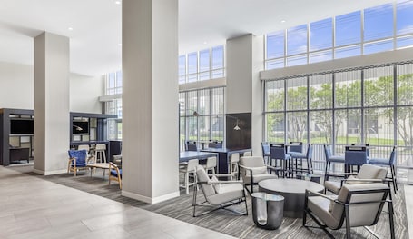 A spacious indoor area with high ceilings, large windows, and modern furniture.