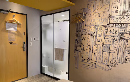 A hotel room with a wooden door, a frosted glass door, and a wall with a detailed mural.